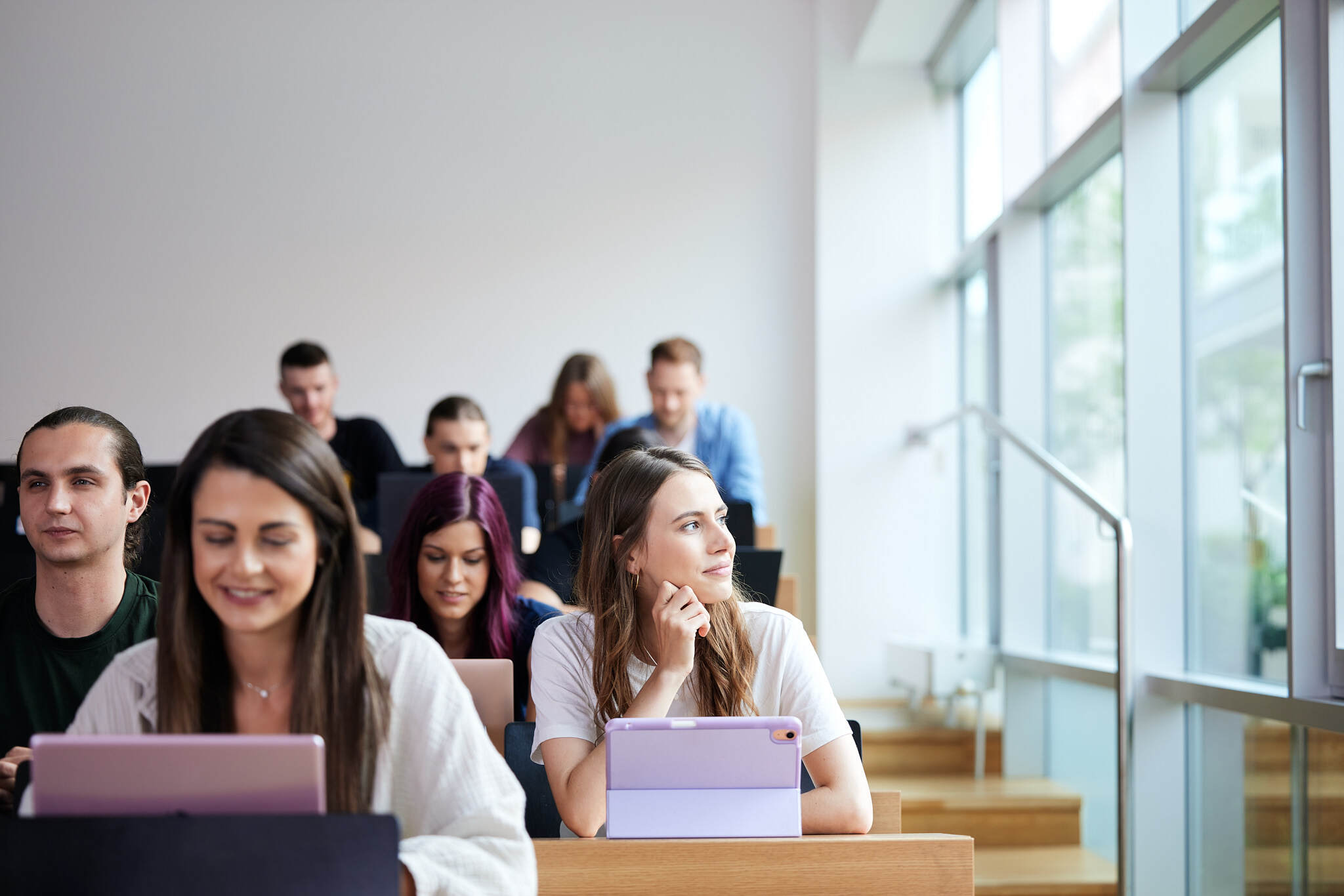Studierende sitzen in einem Hörsaal und arbeiten an Tablets.