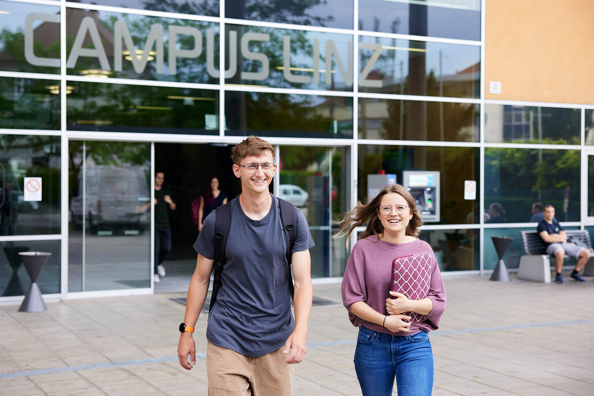 zwei junge Studenten gehen aus einem Gebäude der FH Linz hinaus