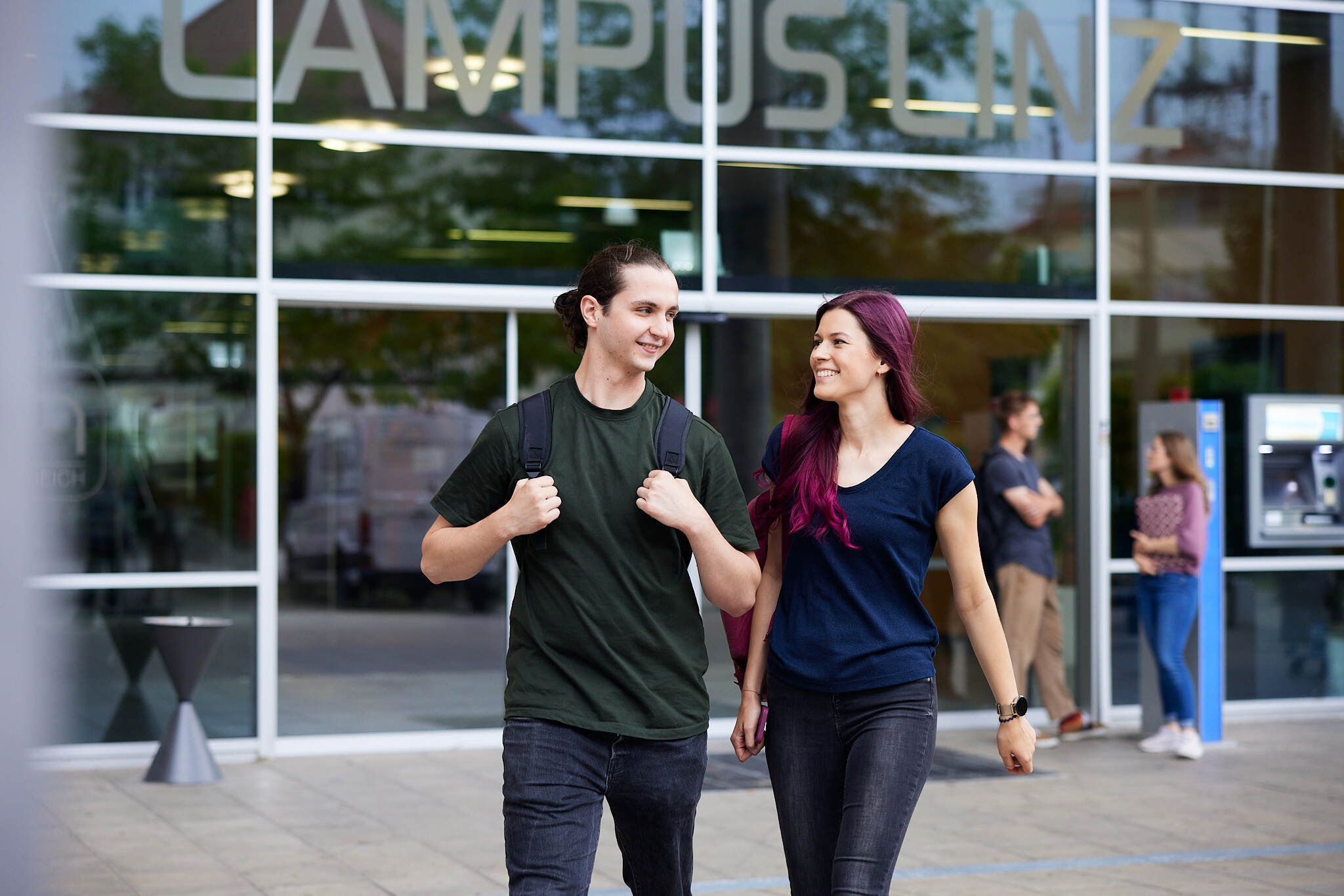 zwei junge Studenten stehen vor einem Campusgebäude der FH Linz